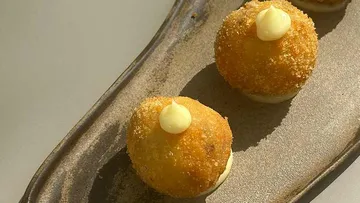 Drei Kroketten mit Sauce auf einem Teller.