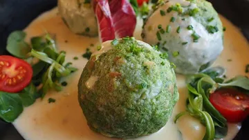 Spinach dumplings with creamy sauce on plate.