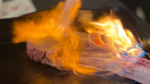 Steak engulfed in flames during cooking.