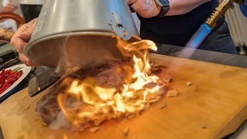 Person torching food on wooden board.