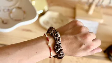 Hand trägt Armband mit Leoparden-Haargummi.