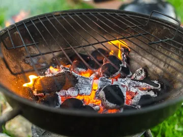 Grill mit glühenden Kohlen und offenen Flammen im Freien.