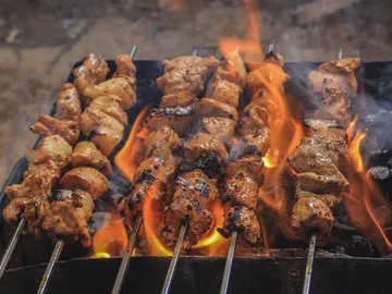 Gegrillte Fleischspieße brutzeln über lebhaften Flammen.