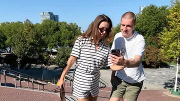 Two people look at a phone outdoors.