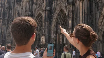 Touristen betrachten Kathedralenfassade, zeigen darauf.