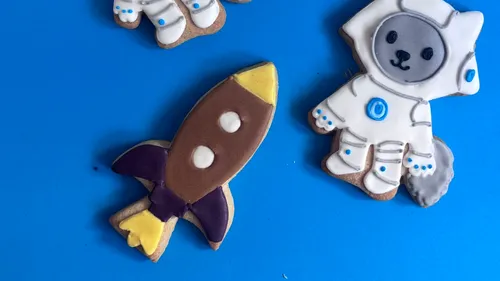 Rocket and astronaut cookies on blue background.