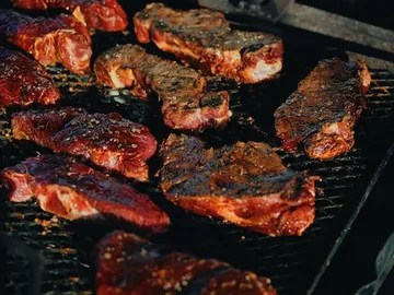 Grill steaks on an outdoor hot grill.