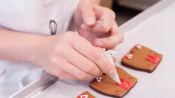 Hände verzieren Kekse mit Zuckerguss.