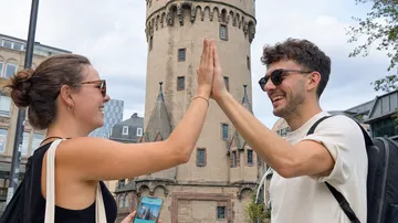 Zwei Personen geben High-Five vor historischem Turm.