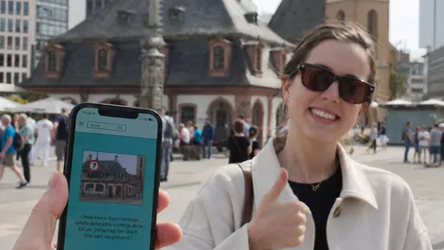 Woman giving thumbs up near historic building.