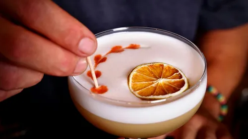 Cocktail mit Zitrusscheibe und Kunst garniert.