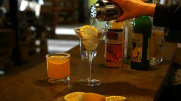Barkeeper gießt Cocktail in Martiniglas.