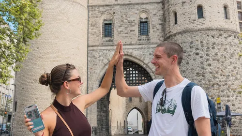 Two people high-fiving near historic gate.