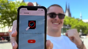 Phone displaying message held by smiling person outdoors.