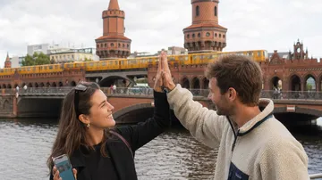 Zwei Personen geben sich High-Five nahe einer Brücke.