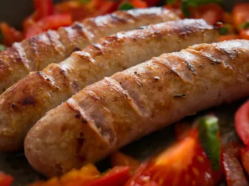 Grilled sausages lie on sliced vegetables.