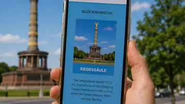 Hand hält Handy mit Berlins Siegessäule-Ansicht.