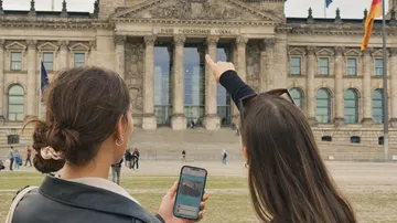 Zwei Frauen draußen, eine zeigt auf den Reichstag.