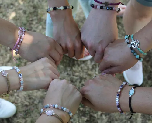 Hands joined in circle wearing bracelets.