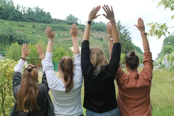 Vier Personen heben draußen Hände hoch.