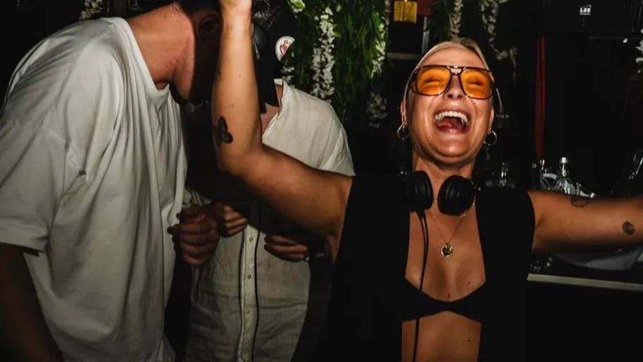 Woman dancing and smiling, wearing headphones, indoors.