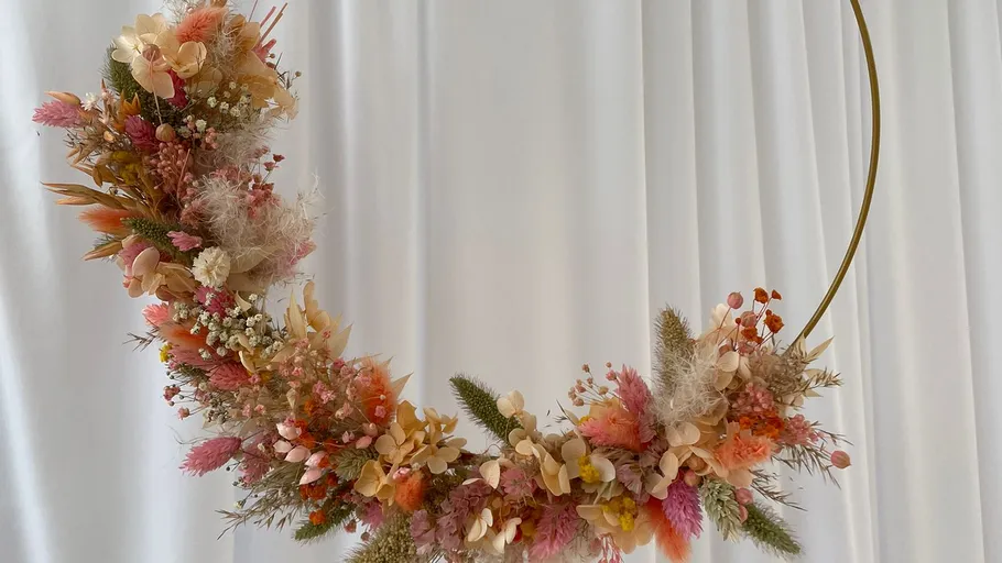 Blumenkranz hängt vor weißem Vorhang.
