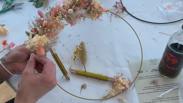 Hände basteln Blumenkranz auf Tisch.