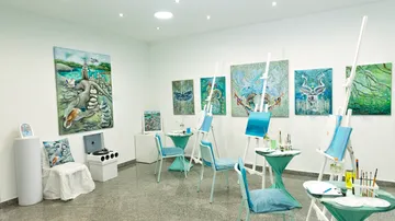 Kunststudio mit Stühlen und Gemälden auf Staffeleien.