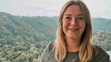 Frau lächelt, Berge im Hintergrund.