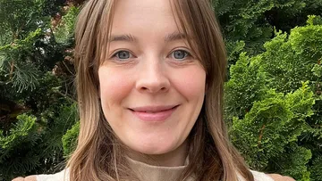 Person smiling in a lush garden.