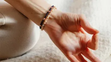 Hand mit Armband in Meditationspose.