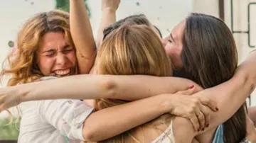 Group of women hugging and smiling joyfully.