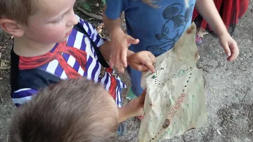 Kinder untersuchen eine Schatzkarte im Freien.