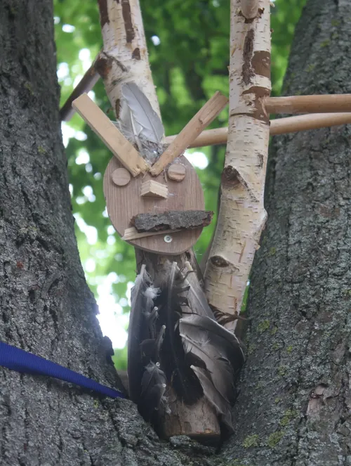 Wooden owl perched in tree branches.