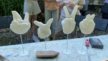 Geformte Hände zeigen Peace-Zeichen auf einem Tisch.