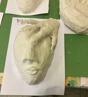 Gipsmaske auf Papier mit angebrachtem Hand.