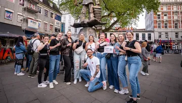 Gruppe posiert am Denkmal auf Stadtplatz.