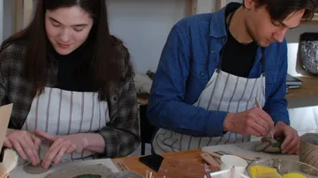Two people crafting pottery at a workshop.