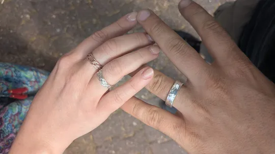 Hands with rings touching outdoors.