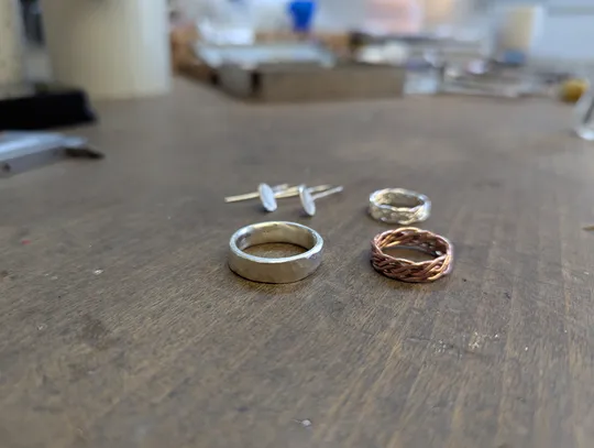 Rings and earrings on wooden table surface.