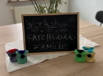 Mini-Häkelwesen neben gerahmter Tafel.