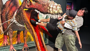 Man rescuing child from dinosaur statue.
