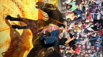 Person rides mechanical bull at fair.