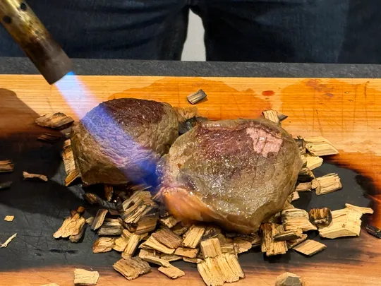 Two steaks seared with a blowtorch on wood chips.