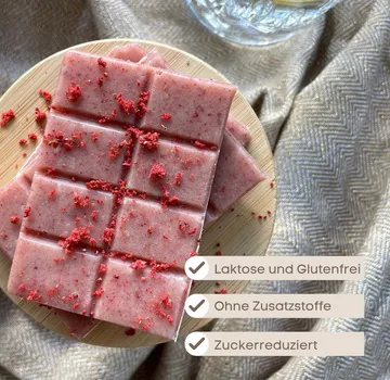 Pink chocolate squares on wooden plate.