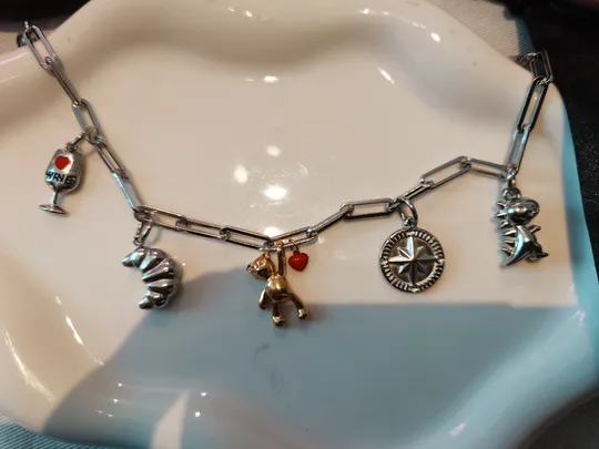 Charm bracelet with various pendants on dish.