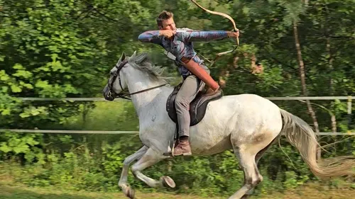 Man on horse shooting arrow in forest
