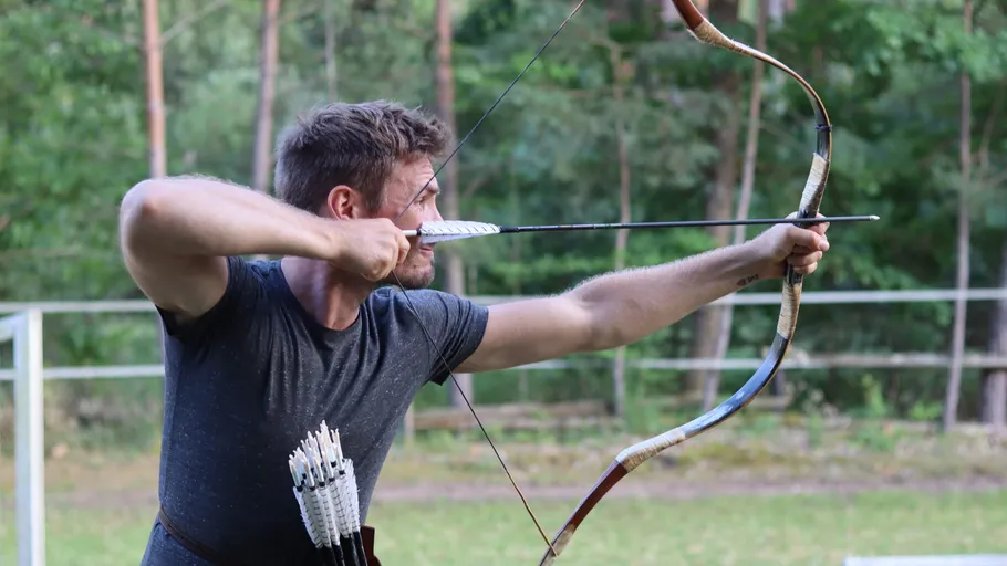 Man aiming bow and arrow outdoors