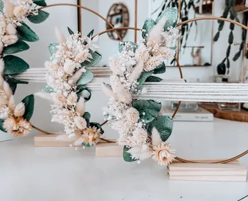 Blumenarrangements auf Holzständern drinnen.