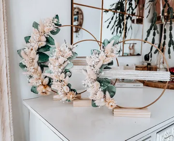 Dekorative Kränze mit Blumen auf weißem Tisch.